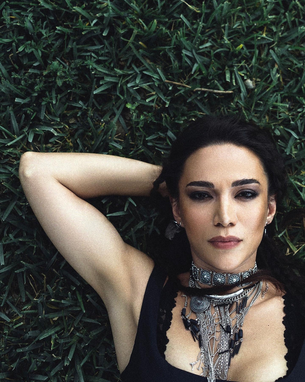 Fashion editorial portrait of Siranush Ambartsumian in a grassy landscape under a dramatic sky.