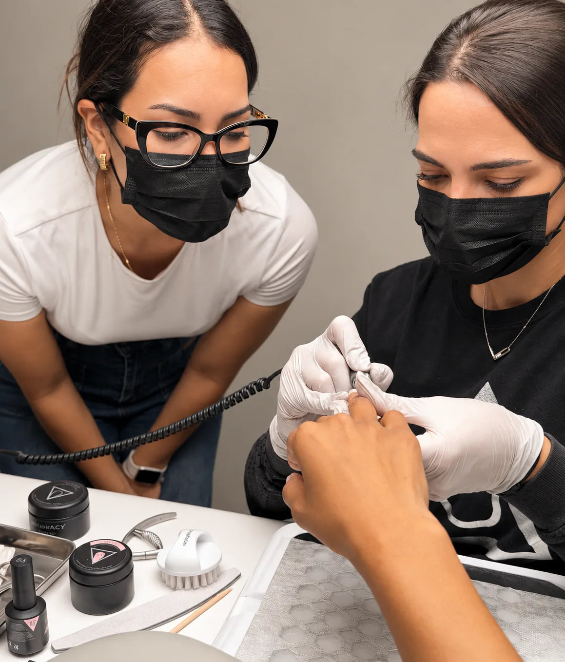 Siranush Ambartsumian guides a student performing a manicure with professional tools during a Nailspiracy Upgrade class.